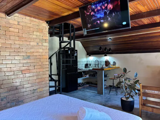 Vista do mezanino para a sala, com TV e parede de tijolo