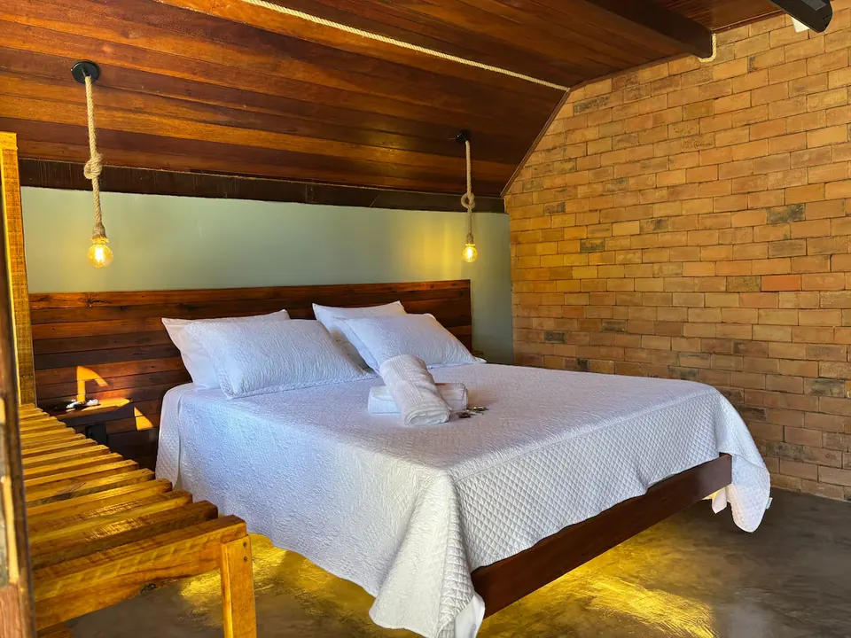 Quarto no mezanino, com cama queen e teto de madeira