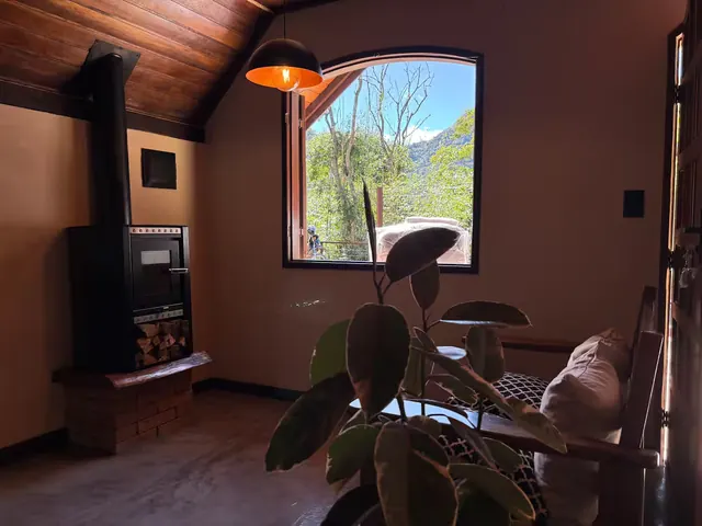 Sala do Chalé Bougainville, com lareira e janela em arco para o vale