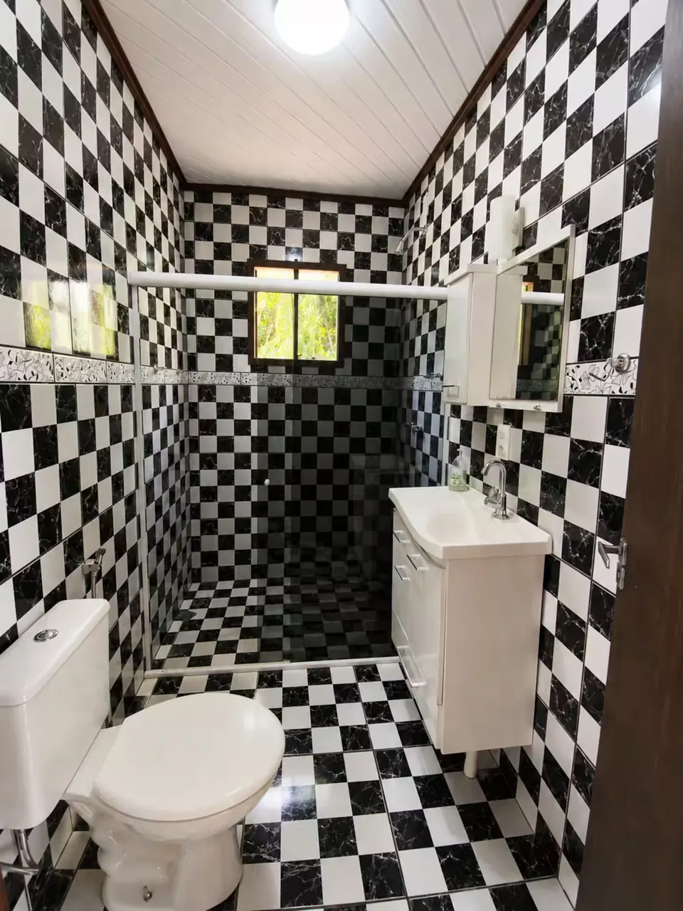 Banheiro com azulejo xadrez preto e branco e box