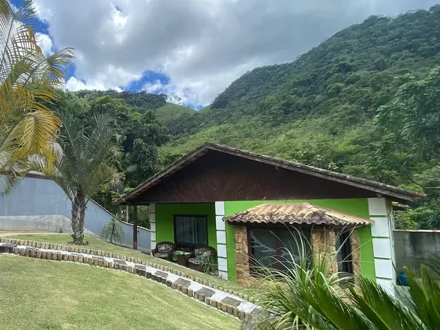 A Casa Verde, de frente, com o gramado à frente e o morro atrás.