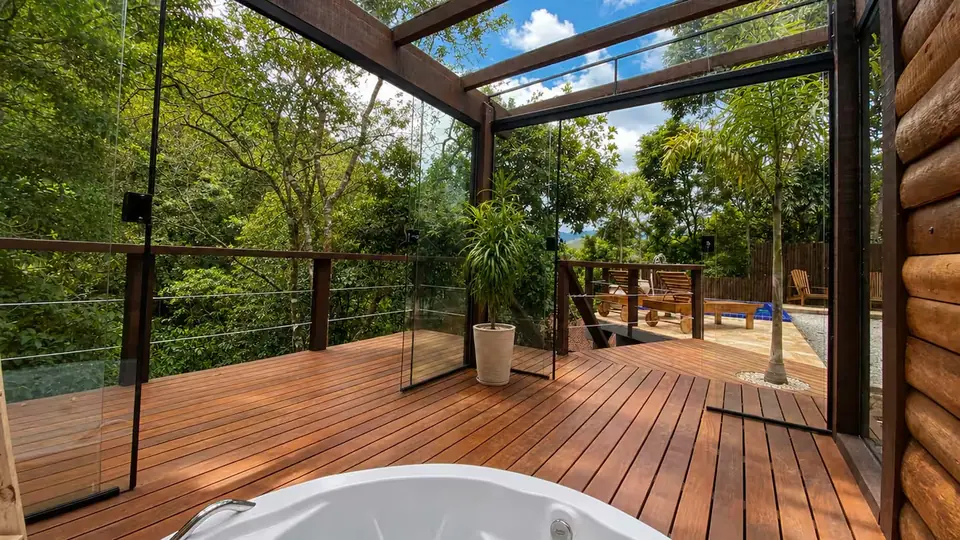 Deck de madeira com a borda da hidromassagem em primeiro plano e a mata atrás