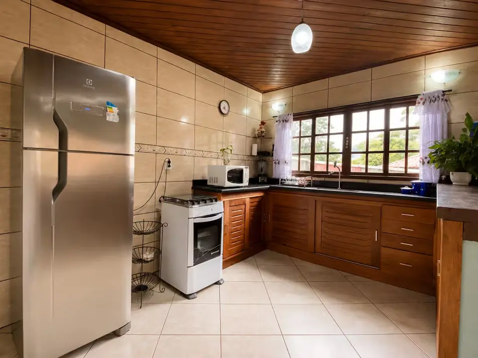 Cozinha equipada, com fogão, geladeira e armários de madeira