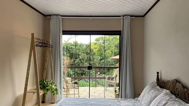 Quarto com lareira visto de frente para a porta de vidro e a varanda
