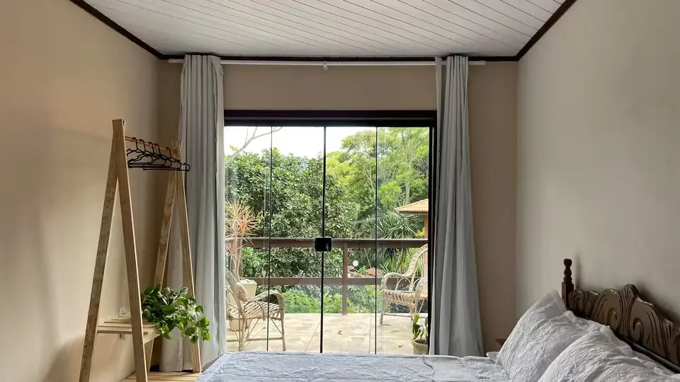 Quarto com lareira visto de frente para a porta de vidro e a varanda