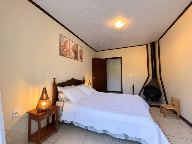 Quarto com lareira no canto e cama de casal com cabeceira de madeira
