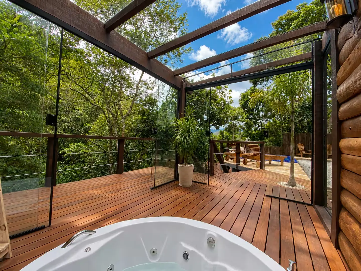 Deck de madeira da Casa Verde, com a hidromassagem e a mata atrás